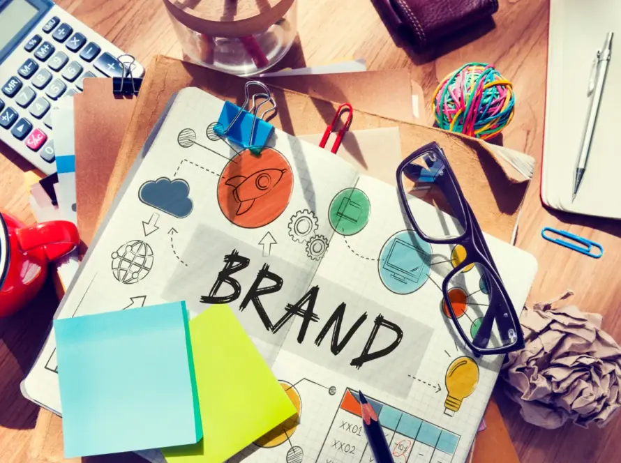 Illustration eines Digital Branding Konzepts mit Skizzen, Farben und Symbolen auf einem Schreibtisch.