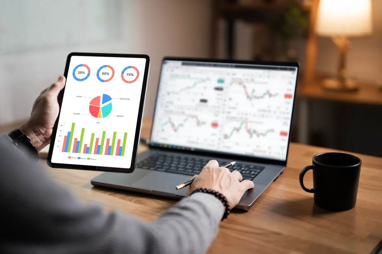 Ein Geschäftsmann analysiert Daten mit einem Tablet und Laptop, auf denen Diagramme und Statistiken angezeigt werden.
