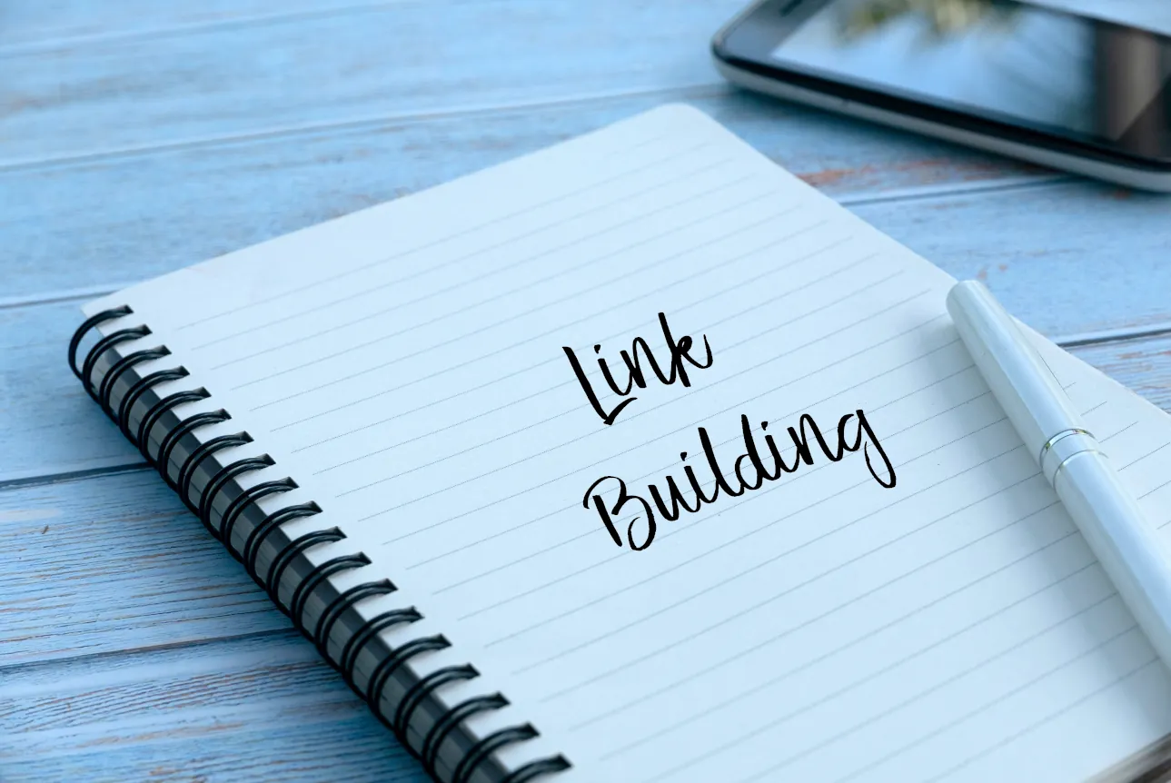 Aufgeschlagenes Notizbuch mit der Aufschrift „Link Building“ auf einem Holztisch, symbolisiert Planung und Strategie im Linkaufbau.